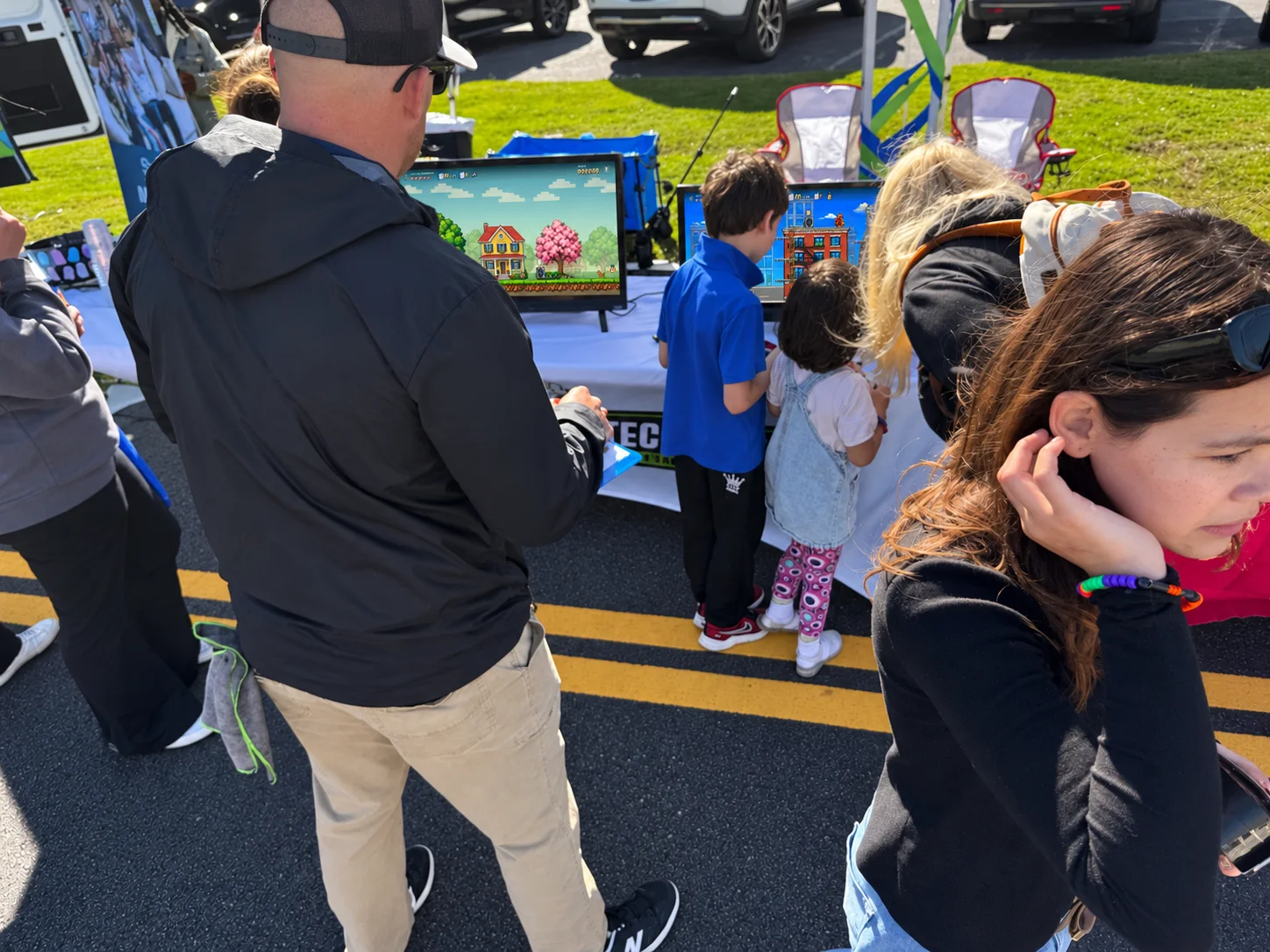 Families pause at the booth to watch and play.